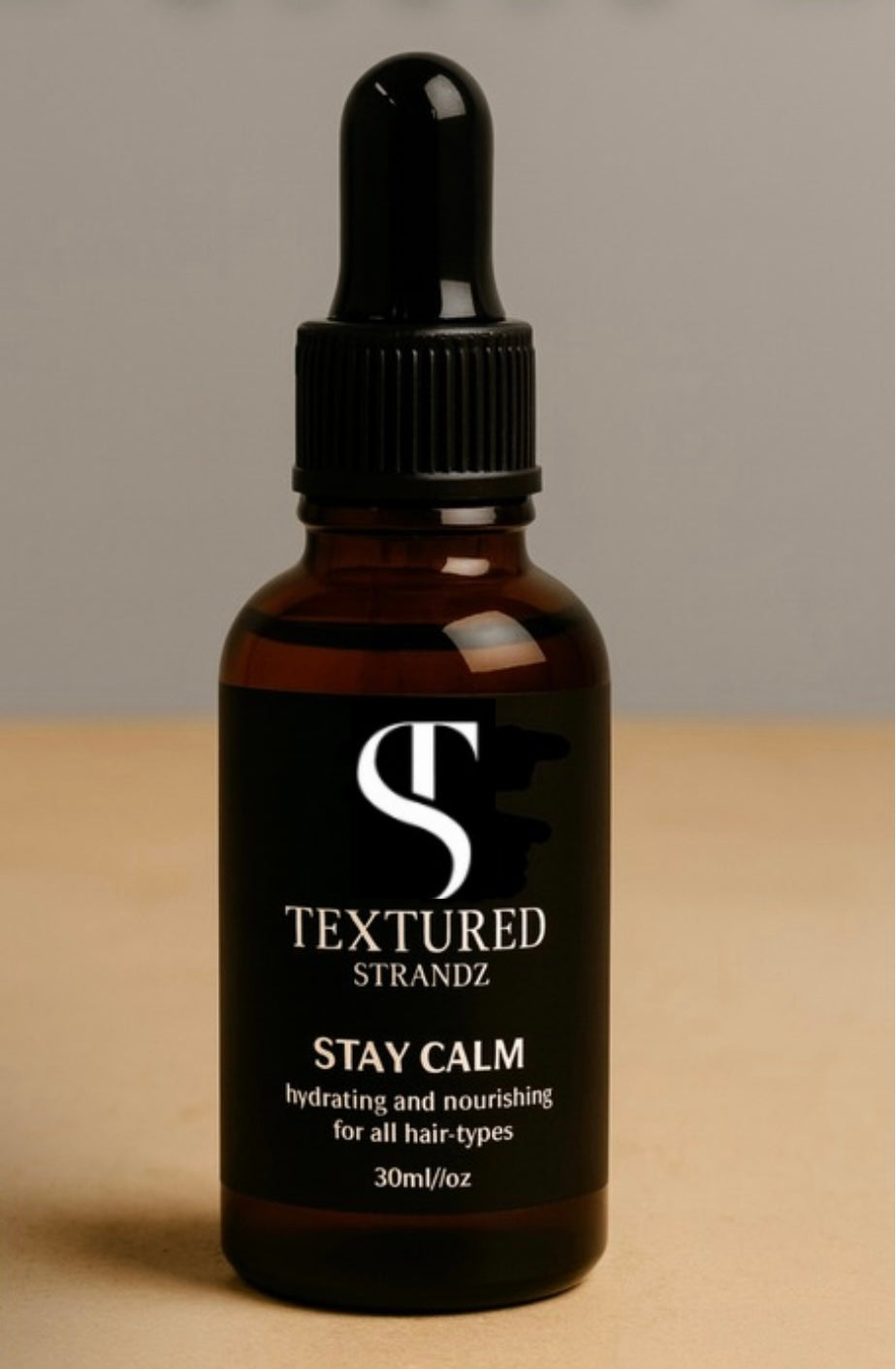 Textured Strandz bottle with dropper on a beige surface