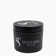 Black jar of 'Textured Strandz' hair product on a white background